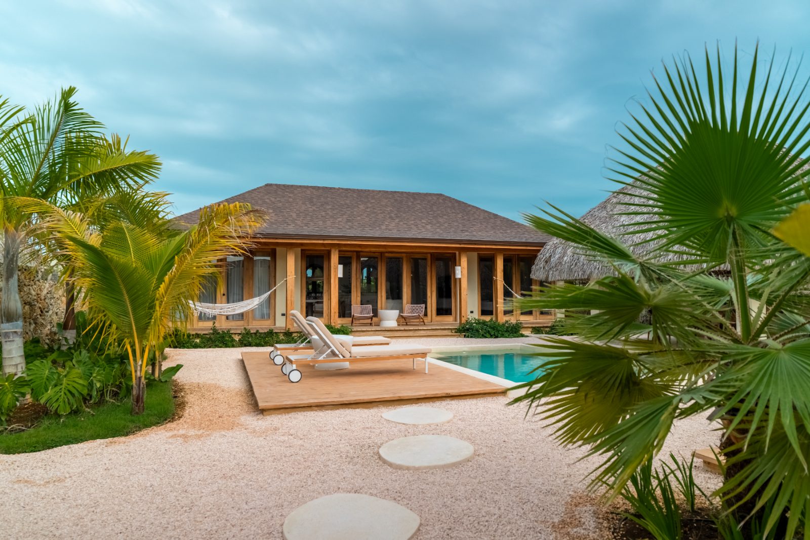 Villa seen from the garden with pool deck and palms in the foreground