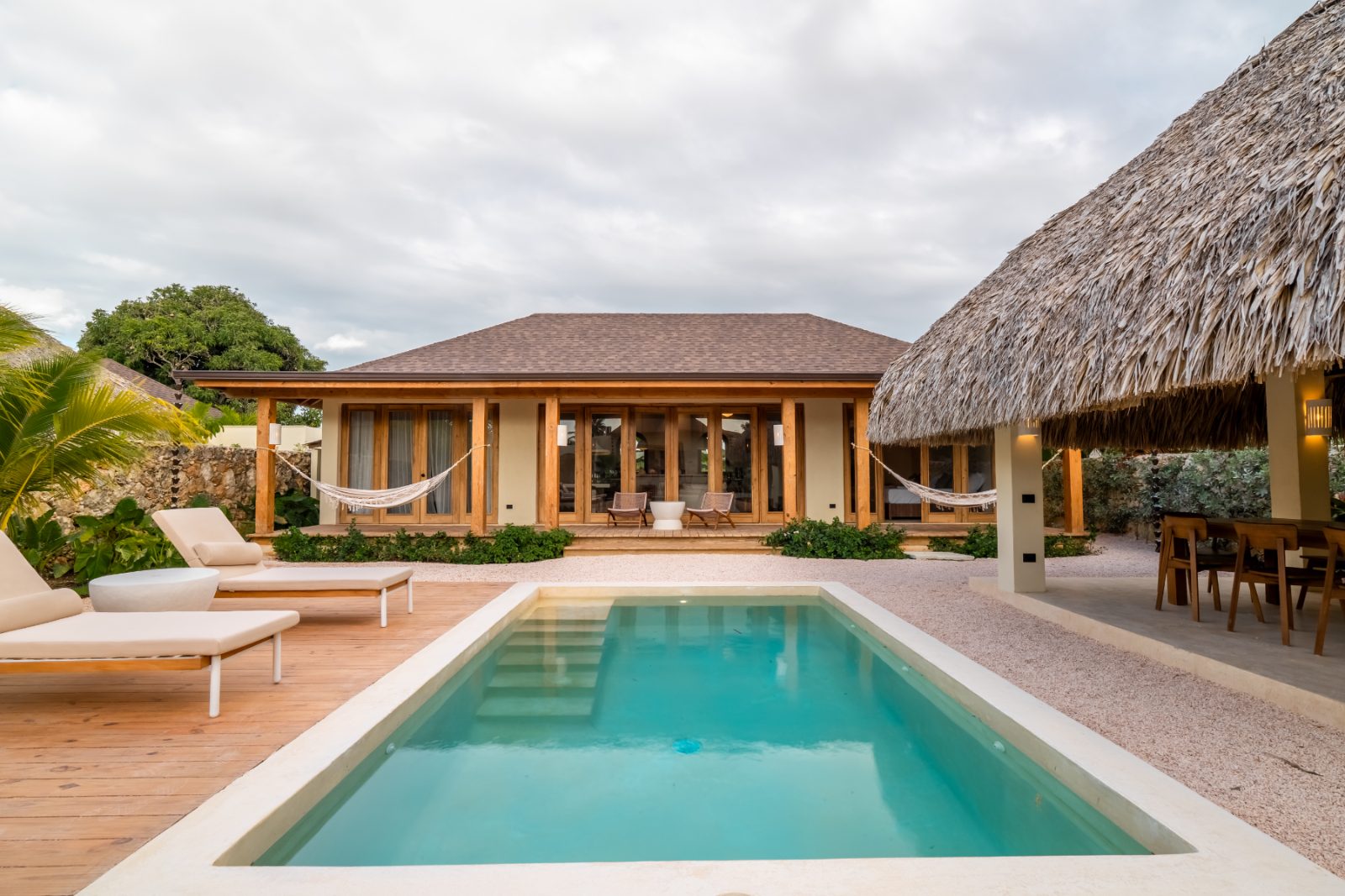 Pool and timber deck with loungers beside the thatched palapa