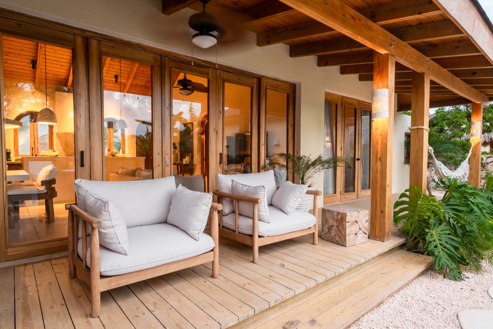 Covered veranda with armchairs and warm interior light at dusk