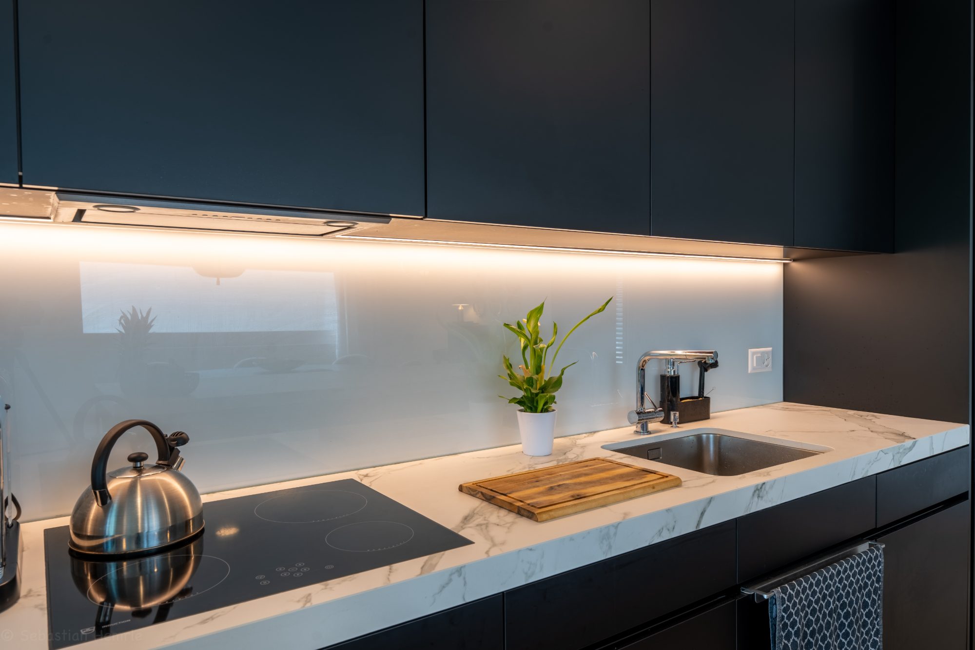 Dark kitchen with marble worktop and underlit cabinets